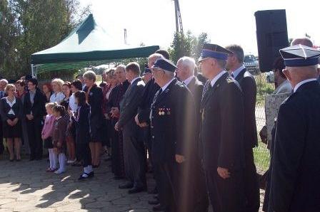 Strażacy i goście stojący w szyku podczas ceremonii wręczenia sztandaru OSP Lewino.