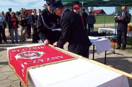 Strażacy w mundurach przy sztandarze OSP Lewino podczas uroczystej ceremonii.