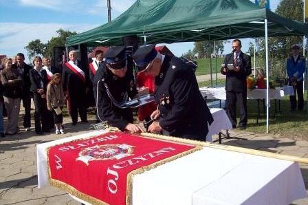 Uroczystość wręczenia sztandaru OSP Lewino z udziałem strażaków pod zielonym namiotem.