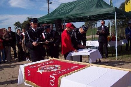 Uroczystość z udziałem strażaków OSP Lewino i sztandaru pod zielonym namiotem.