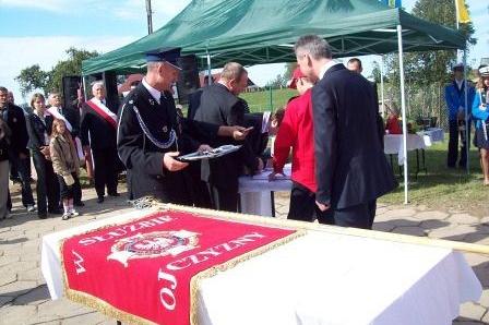 Ceremonia przekazania sztandaru OSP Lewino z uczestnikami pod zielonym namiotem.