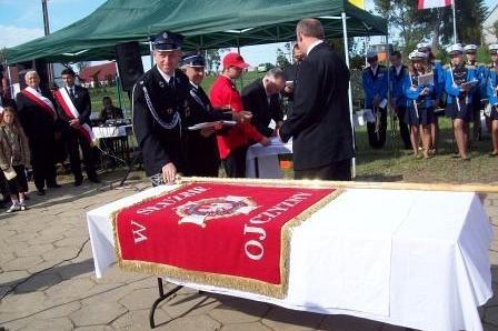 Przekazanie sztandaru OSP Lewino, w tle strażacy i goście.