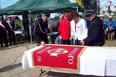 Uroczystość przekazania czerwonego sztandaru OSP Lewino na świeżym powietrzu.