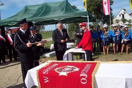 Ceremonia wręczenia sztandaru dla OSP Lewino z uczestnikami w galowych strojach.
