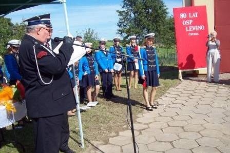 Przemówienie oficjela do strażaków OSP Lewino w mundurach na ceremonii.
