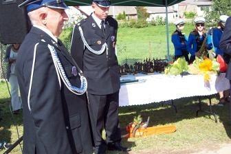 Dwóch strażaków OSP Lewino w galowych mundurach na zbiórce plenerowej.