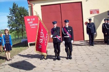 Członkowie OSP Lewino ze sztandarem przed strażnicą.