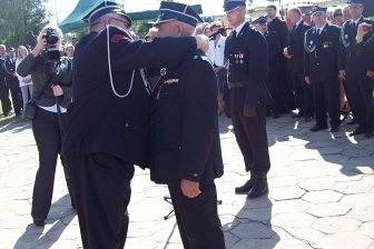 Członkowie OSP Lewino w ciemnych mundurach stojący na zewnątrz podczas uroczystości.