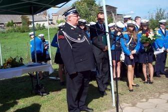 Mężczyzna w mundurze OSP Lewino przemawia pod namiotem podczas uroczystości.
