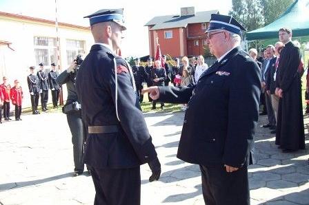 Mundurowi OSP Lewino podczas oficjalnej ceremonii, jeden oddaje honor drugiemu.