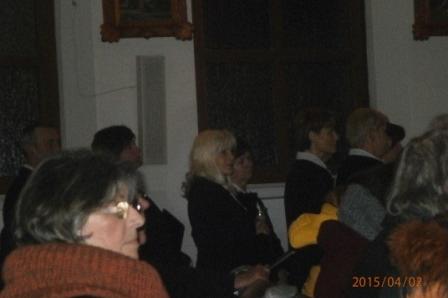 Uczestnicy wieczornego requiem w Gdyni, skupieni w przyciemnionym pomieszczeniu.
