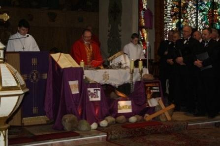 Księża w szatach liturgicznych przy ołtarzu podczas mszy requiem w kościele.