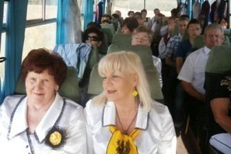Dwie kobiety w białych strojach siedzące na Zjeździe Kaszubów, w tle inni uczestnicy.