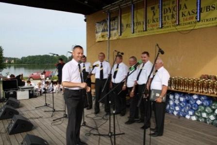 Męski chór podczas występu plenerowego nad wodą.