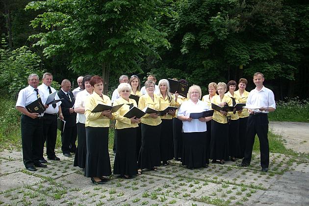 Grupa członków chóru w strojach z nutami, stojąca na zjeździe w Chwaszczynie.