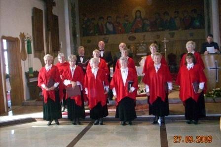 Chór parafialny w czerwonych szatach podczas przeglądu w kościele.