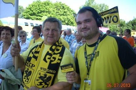 Dwóch uśmiechniętych mężczyzn w żółto-czarnych strojach na Zjeździe Kaszubów.