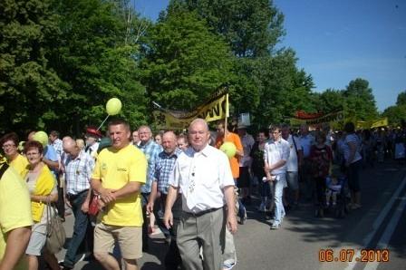 Uczestnicy XV Zjazdu Kaszubów w żółtych strojach idą w słonecznym pochodzie.