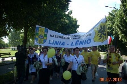 Grupa ludzi trzymająca transparent GMINA LINIA LENTO na zlocie Kaszubów.