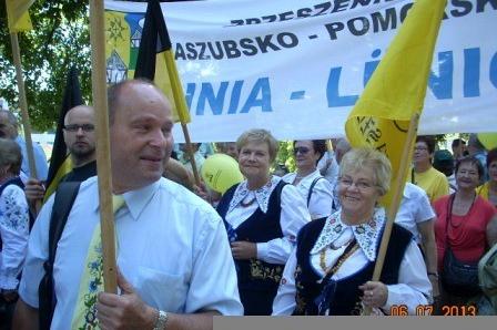 Uczestnicy Zjazdu Kaszubów z flagami i banerem Gmina Linia.