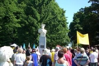 Uczestnicy Zjazdu Kaszubów gromadzą się wokół białej figury na świeżym powietrzu.