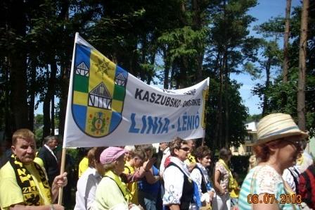 Zjazd Kaszubów: ludzie niosący flagę z kaszubskim herbem Gminy Linia.