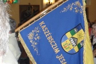 Niebieski sztandar kaszubski z napisem i żółtymi ozdobami.