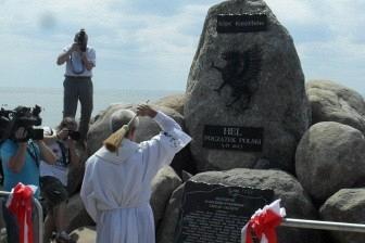 Ludzie podziwiają Kopiec Kaszubów, duży kamienny monument pod pochmurnym niebem.