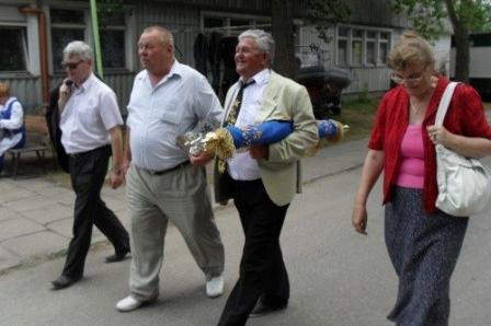 Cztery osoby, trzech mężczyzn i kobieta, idą ulicą po uroczystości na Helu.