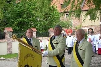 Mężczyźni w uroczystych strojach przy podium z banerem na obchodach 800-lecia Żukowa.