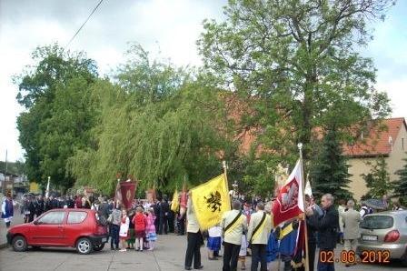 Uczestnicy obchodów 800-lecia Żukowa z flagami idący ulicą.