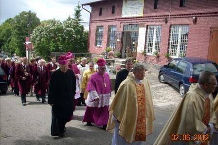 Uroczysta procesja duchownych i wiernych przed budynkiem w Żukowie podczas obchodów.