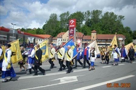 Uroczysty pochód ludzi w historycznych strojach na ulicy Żukowa podczas jubileuszu.