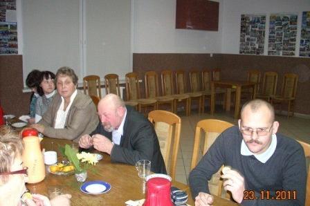 Goście siedzą przy stole podczas Zabawy Andrzejkowej 2011, rozmawiając i jedząc.