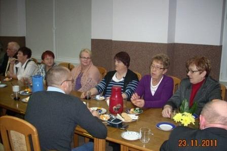 Uczestnicy Zabawy Andrzejkowej siedzą przy stole podczas spotkania towarzyskiego.