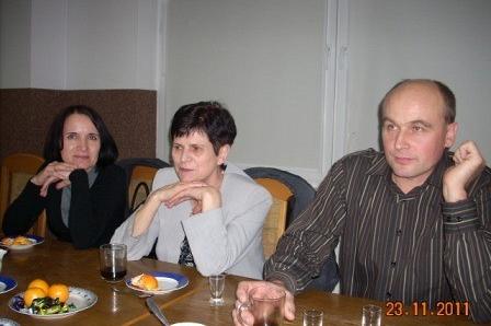 Uczestnicy andrzejkowej zabawy siedzą przy stole, słuchając.