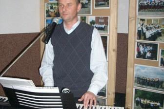 Muzyk w białej koszuli i ciemnej kamizelce gra na keyboardzie na Zabawie Andrzejkowej.