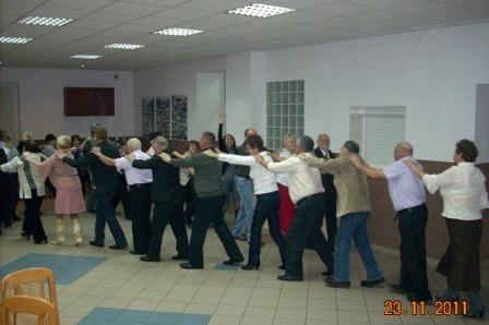 Uczestnicy zabawy andrzejkowej w rzędzie, łączący ręce do wspólnego tańca.