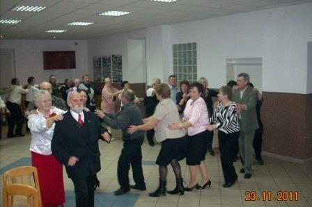 Roztańczona grupa dorosłych podczas Andrzejkowej zabawy w sali.