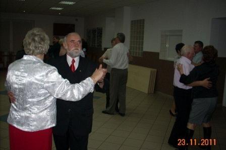 Goście andrzejkowej zabawy tańczą w parach na sali.
