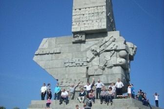 Masywny pomnik Obrońców Wybrzeża na Westerplatte z ludźmi u podstawy.
