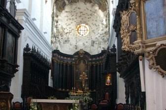 Wnętrze zabytkowej gotyckiej katedry w Gdańsku z ołtarzem głównym i wysokim sklepieniem.