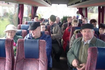 Pasażerowie autokaru, wielu w kapeluszach, w drodze na targi ogrodnicze.