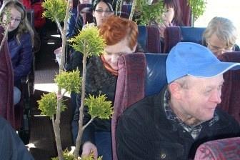 Tłum ludzi wśród zielonych roślin na targach, mężczyzna w niebieskiej czapce na pierwszym planie.