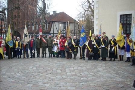Kaszubi w tradycyjnych strojach z flagami świętują na placu w Słupsku.