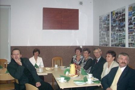 Grupa osób świętująca 5-lecie ZKP Linia przy stole z napojami i świecą.