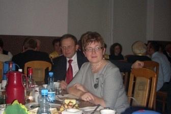 Kobieta uśmiecha się przy stole pełnym jedzenia podczas uroczystości 5-lecia ZKP.