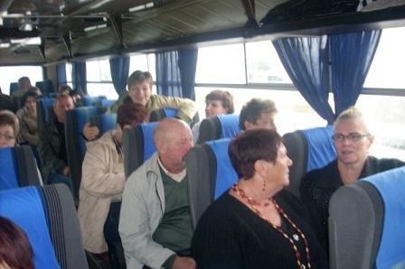 Uczestnicy wycieczki ZKP w autobusie, siedzący i stojący, w tle okno.