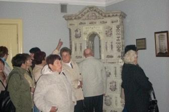 Uczestnicy wycieczki ZKP O/LINIA podziwiają wnętrze z ozdobnym piecem.