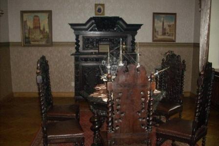 Wystawna, historyczna sala z masywnymi drewnianymi meblami i obrazami.